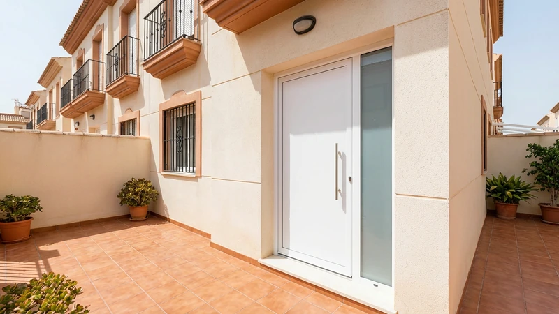 Puerta de entrada blanca con luz lateral en piso de Murcia